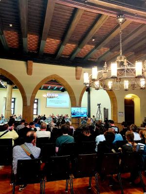 Saal des historischen Rathauses während der Stadtratssitzung mit Menschen auf Stühlen und an Tischen sitzend