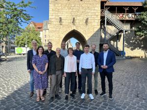 Gruppe von Menschen steht vor dem Johannistor in Jena und lächelt in die Kamera.