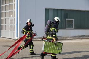 Zwei Feuerwehrmänner mit Schlauch und Equipement.