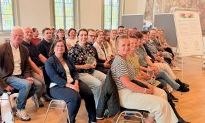 Viele Menschen in einem Raum und alle schauen in die Kamera