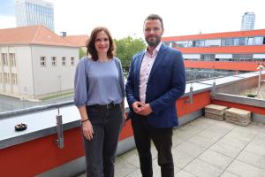 Mann und Frau stehen auf einer Terrasse mit Jena im Hintergrund.