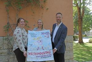 Drei Personen mit Plakat