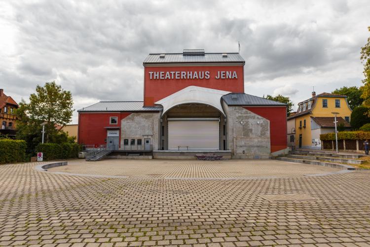 Ein großer Platz mit einem rotem Haus mit einer Bühne