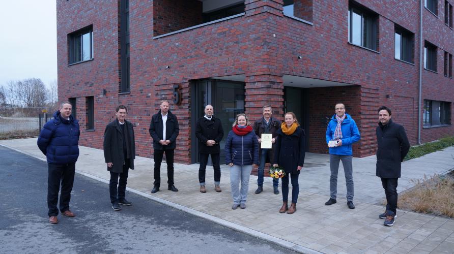 Mehrere Personen stehen vor einem Backsteinhaus