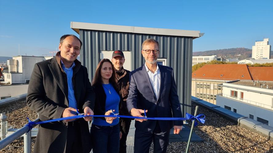 Bürgermeister Christian Gerlitz (v.l.), Kerstin Wuthenow (Ehrenamtliche Stadttaubenhilfe) und  Detlef Graba (Director Asset Management Technik und Nachhaltigkeit Real I.S. AG) schneiden ein Band vor dem neuen Taubenhaus durch. Hinter ihnen steht Taubenwart Torsten Schulz.