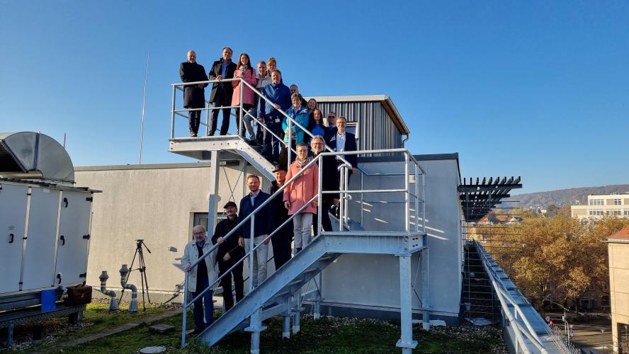 Auf einer Treppe stehen eine Reihe von Männern und Frauen für ein Gruppenbild aufgereiht.