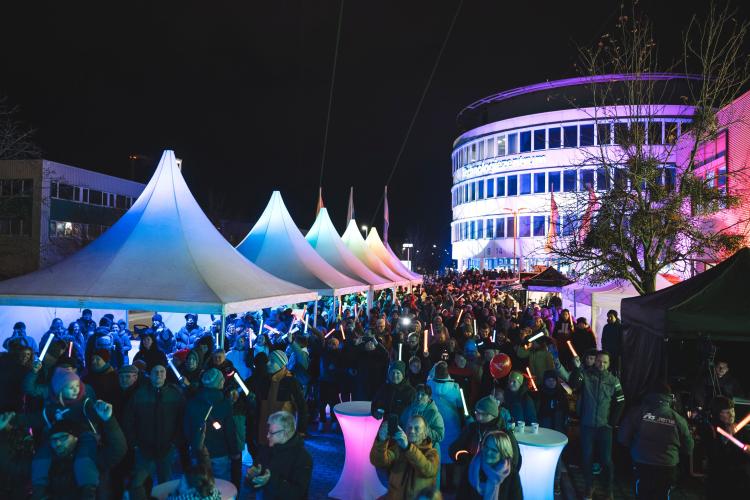 Gebäude in Jena leuchten in der Dunkelheit, viele Menschen sind zu sehen.