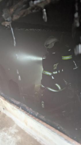 Ein Feuerwehrmann in Vollausrüstung geht durch einen verrauchten Keller.