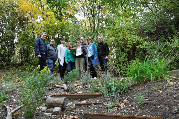 Gruppenbild: acht Personen. Eine Frau hält eine Urkunde in der Hand
