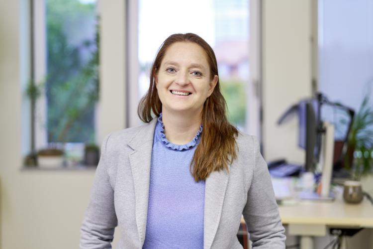 Frau sitzt an einem Tisch und lächelt in die Kamera