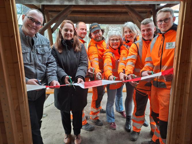 Acht Männer und Frauen schneiden ein Band durch.