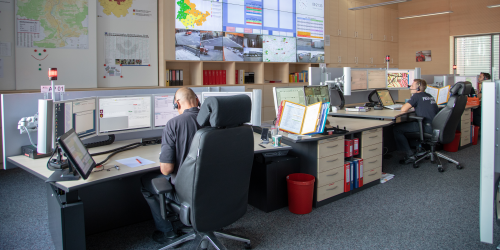 Drei Männer bei der Arbeit in der Leitstelle Jena. Sie sitzen vor Rechnern und mehreren Bildschirmen.