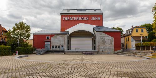 Ein großer Platz mit einem rotem Haus mit einer Bühne