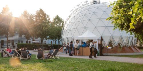 In einem Park steht ein kuppelförmiger Pavillion. 