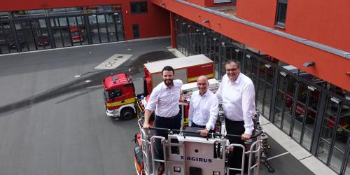 Die Dezernenten Koppe, Horn und Dannenberg (v.l.) stehen in einem Beöfrderungskorb einer Drehleiter. Die Drehleiter ist ausgefahren. Das GAZ und Feuerwehrautos sind im Hintergrund zu sehen. 