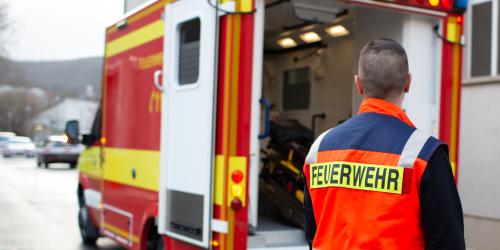 Ein Rettungswagen der Feuerwehr, ein Helfer im Vordergrund