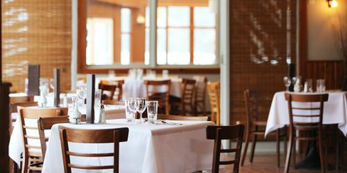 Leerer Gastraum mit gedeckten Tischen und weißen Tischtüchern