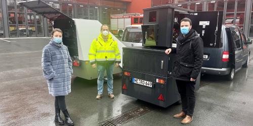 Drei Menschen mit Maske vor technischen Geräten