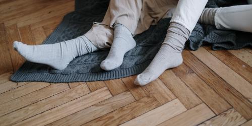 Mehrere Füße in Socken auf einem Holzboden