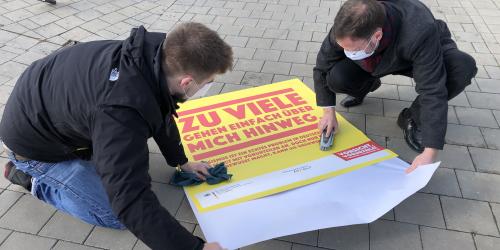 Zwei Menschen kleben einen Bodenaufkleber