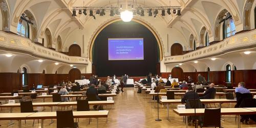 Ein großer Saal mit Tischen, an denen Menschen sitzen