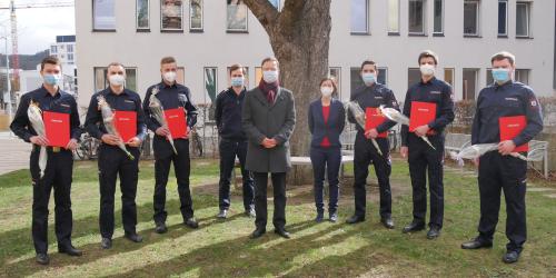 Acht Männer und eine Frau schauen in die Kamera, alle tragen Masken