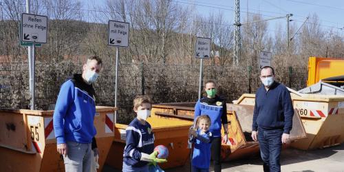 Drei Erwachsenen und zwei Kinder ahebn Mülltüten in der Hand