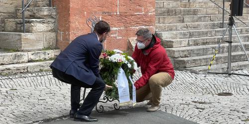 Zwei Männer legen einen Kranz nieder