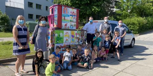 Kinder und Erwachsenen stehen vor einem bunt bemalten Gerät