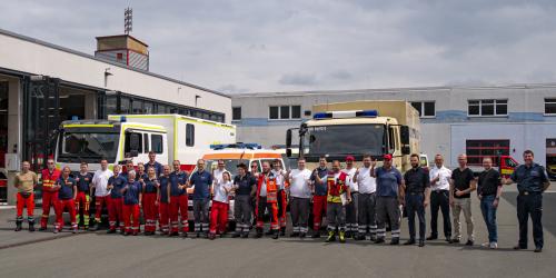 Viele Menschen vor Einsatzfahrzeugen des Katastrophenschutzes