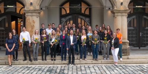 Eine große Anzahl an Personen steht im Außernbereich vor einem Gebäude