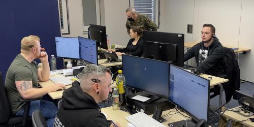 Vier Personen in einem Raum am Telefon