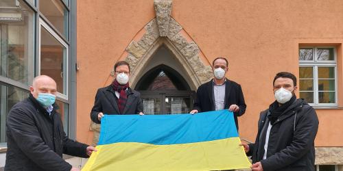 Vier Männer halten eine Fahne