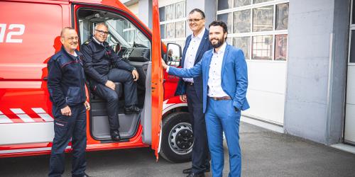 Vier Menschen an einem Feuerwehrwagen