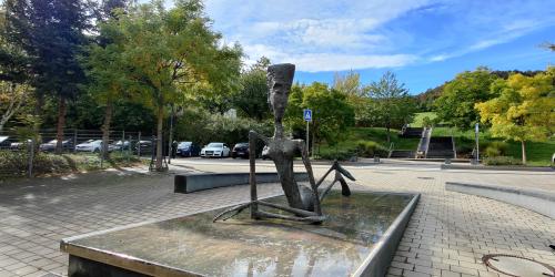 Eine Plattform mit Wasser auf der eine dünne, große Frauenfigur liegt.