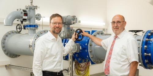 Zwei Männer vor großen Wasserrohren