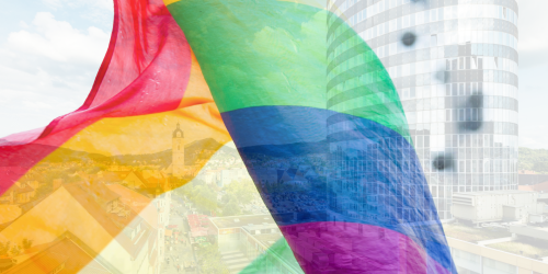 Blick auf die Innenstadt durch eine wehende Regenbogenfahne