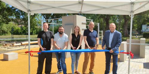 Vier Männer und eine Frau (Mitte) schneiden ein Band mit je einer Schere durch.