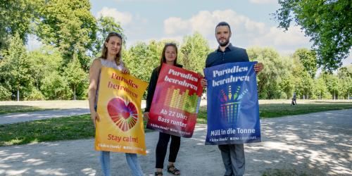 Drei Personen halten je ein Plakat in die Kamera