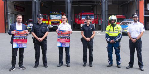 Feuerwehrleute und Polizisten vor einer Feuerwehr mit geöffneten Toren