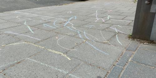 Kreidepfeile markieren auf dem Gehweg den Schulweg von Kindern, die die Westschule besuchen.