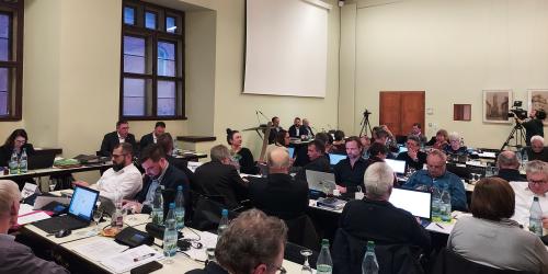 Mitglieder des Stadtrates sitzen an Tischen im historischen Rathaus