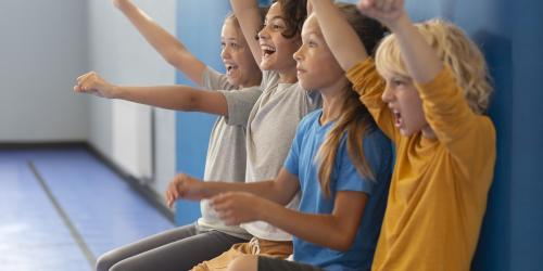 Kinder schauen begeistert vom Spielfeldrand zu.