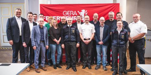 Eine Gruppe von Menschen steht nebeneinander und lacht in die Kamera