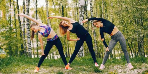 Drei Frauen machen draußen Gymnastik.