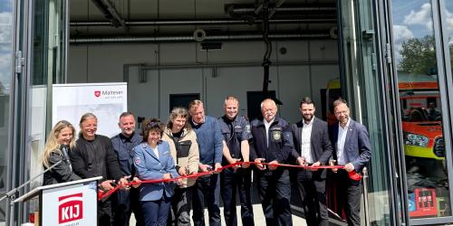 Eine Gruppe aus Männern und Frauen zerschneidet rotes Band.