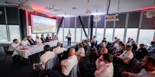 Ein Mann spricht in ein Mikrofon vor einem Publikum.