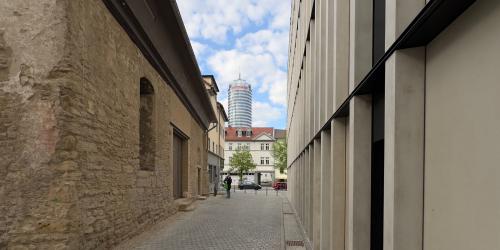 Ein Durchgang – links ein mittelalterliches Gebäude, rechts ein modernes Gebäude