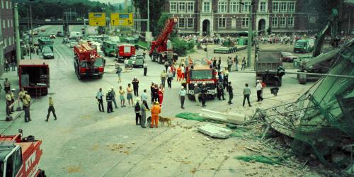Menschen schauen auf ein eingestürztes Gebäude.
