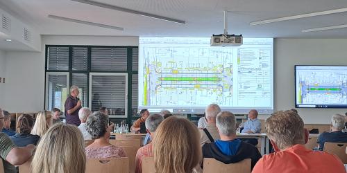 Menschen sitzen in einem Besprechungsraum und folgen einem Vortrag
